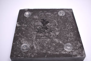 zoomed in photo of bottom of gray square coaster with clear rubber footies