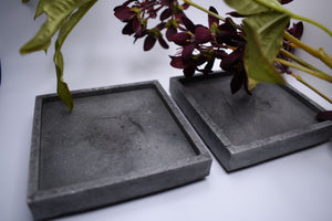 2 gray square coasters with dark purple flowers used as decoration